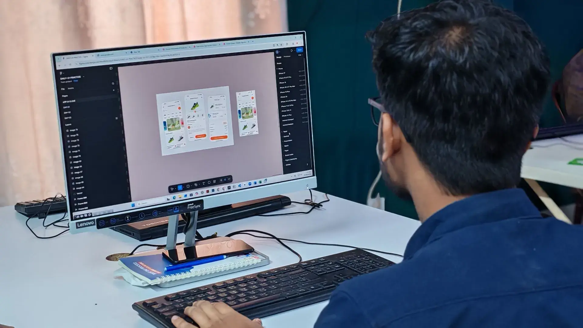 A designer laying out app screens on a large monitor.