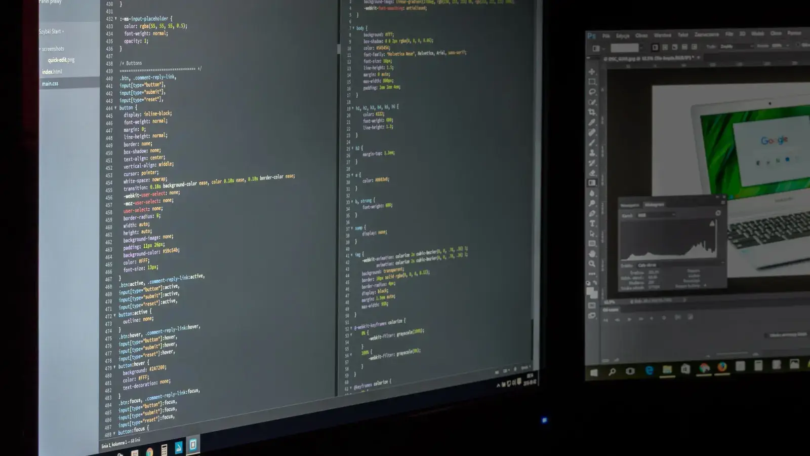 Stylesheet code open across two monitors in a dark room.